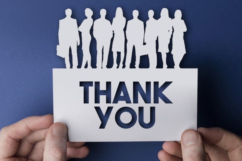 Hands holding a thank you white card business team people sign
